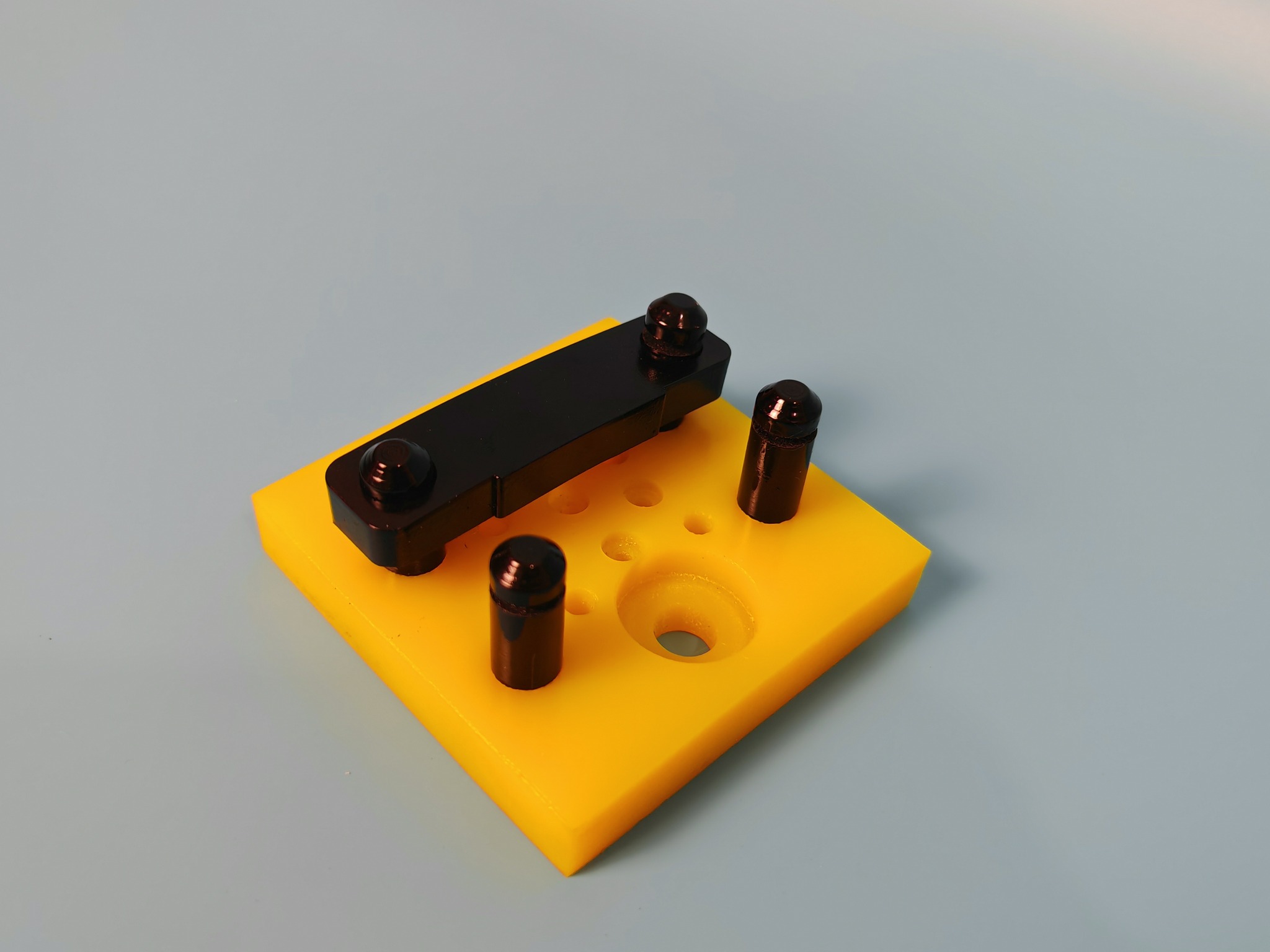 Gelbe Adapterplatte mit schwarzen Befestigungselementen.