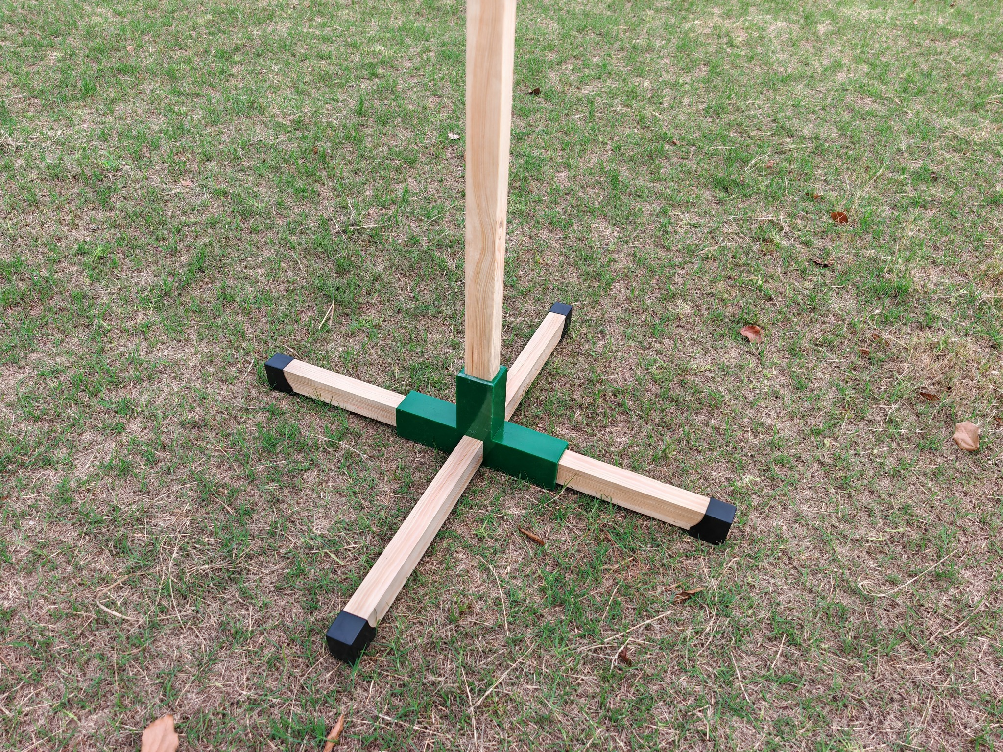 Grüner Verbinder mit Holzprofilen als Standfuß im Außenbereich.